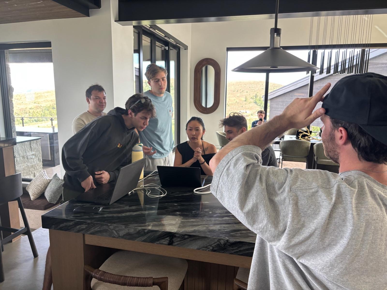Teammates gathered around a laptop in the kitchen